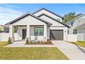 Modern two-story home with white siding, dark trim, a covered porch, and a driveway leading to an attached garage at 3006 E Columbus Dr, Tampa, FL 33605