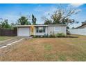 Well-maintained single-story home with a yellow door, tidy landscaping, and a private driveway at 6524 14Th N St, St Petersburg, FL 33702