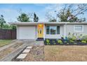 Charming home features a bright yellow door, attached garage, and lovely landscaping at 6524 14Th N St, St Petersburg, FL 33702
