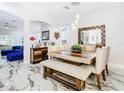 Modern dining room featuring a wooden table, white chairs, and decorative mirror at 16829 Midsummer Ln, Spring Hill, FL 34610