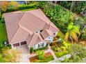 Aerial view of home, showcasing landscaped grounds, three-car garage, and tile roof, nestled among mature trees at 5212 Candler View Dr, Lithia, FL 33547