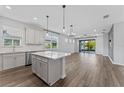 Open-concept kitchen and living area with an island, modern light fixtures, and wood-look flooring at 6421 Mooring Line Cir, Apollo Beach, FL 33572