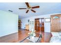 Comfortable living room with glossy hardwood floors, ceiling fan and bright front door at 5624 Mccoy Ct, Zephyrhills, FL 33542
