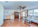 Inviting living room with warm wood flooring, ceiling fan, and plenty of natural light at 5624 Mccoy Ct, Zephyrhills, FL 33542