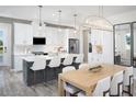 Modern kitchen featuring white shaker cabinets, a large island with seating, and stainless steel appliances at 11860 Boundless Ter, Venice, FL 34293