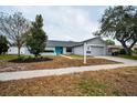 Single-story home with teal door, attached garage, for-sale sign, and landscaping at 520 Meravan Dr, Palm Harbor, FL 34683