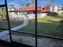 View from the condo unit to the community pool area with lounge chairs, a covered area, and lush landscaping at 3271 Beneva Rd # 104, Sarasota, FL 34232