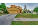 Two-story home with yellow siding, attached garage, and driveway at 9112 Bell Rock Pl, Land O Lakes, FL 34638