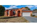 Single-story home with stucco exterior, arched entryway, and attached garage at 4401 Plumosa St, Spring Hill, FL 34607