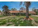 Charming single story home with a well-manicured lawn, mature trees, and cozy front porch at 1055 Riverside Ridge Rd, Tarpon Springs, FL 34688