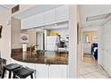 Open kitchen with breakfast bar, white cabinets, and view to bedroom at 1700 Cove Ii Pl # 310, Sarasota, FL 34242