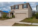 Two-story home with a two-car garage, brown shutters, and a paved driveway at 17002 Oval Rum Dr, Wimauma, FL 33598