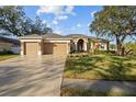 Charming single-story home featuring a well-manicured lawn, three-car garage, and beautiful arched entryway at 10101 Paddock Oaks Dr, Riverview, FL 33569