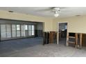 The open-concept living room has plantation shutters, concrete floors, and exposed wall framing at 15816 2Nd St E, Redington Beach, FL 33708