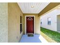 Covered entryway with a red front door and a small welcome mat at 10615 Dawns Light Dr, Riverview, FL 33578