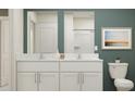 Bathroom with double vanity, white cabinets, and green accent wall at 32212 Jamaica Caper Way, San Antonio, FL 33576