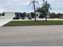 Newly renovated home with a modern exterior, featuring a lush lawn and driveway at 87 Rotonda Cir, Rotonda West, FL 33947