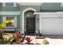 Elegant home entrance with a decorative archway, well-maintained garden, and a two-car garage at 11351 Callaway Pond Dr, Riverview, FL 33579