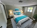 Comfortable bedroom featuring a queen bed, soft gray carpet, and tasteful turquoise accents at 5038 Galaxy Dr, New Port Richey, FL 34652