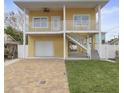 Front exterior view of a two-story yellow home with a balcony, garage, and driveway at 13122 4Th E St, Madeira Beach, FL 33708