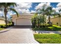 Tan house with a large garage and lush landscaping at 1847 Pacific Dunes Dr, Sun City Center, FL 33573