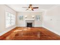 Living room with hardwood floors, fireplace, large windows, and ceiling fan at 323 W Hanna Ave, Tampa, FL 33604