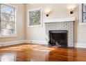 Living room featuring hardwood floors, a white brick fireplace, and ample natural light at 323 W Hanna Ave, Tampa, FL 33604