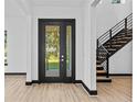 Light-filled foyer with black framed glass door, and modern staircase with wooden steps at 6303 Barton Rd, Plant City, FL 33565