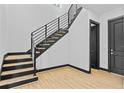 Modern staircase with wooden steps and black metal railings near entryway and black door at 6303 Barton Rd, Plant City, FL 33565