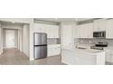 Modern kitchen with stainless steel appliances, white cabinets, and a large island with quartz countertops at 11726 Renaissance Blvd, Venice, FL 34293
