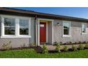 Front exterior of a single-Gathering home with a red front door, large windows, and landscaping at 866 Rudy Quail Pl, Sun City Center, FL 33573