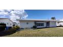 Quaint single-story home featuring a front yard with an attached garage and tidy landscaping at 9350 Mainlands W Blvd, Pinellas Park, FL 33782