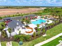 Aerial view of a community pool, cabana, jacuzzi and splashpad surrounded by lush landscaping at 17390 Moonflower Dr # 201, Venice, FL 34293