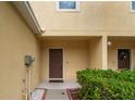 Cozy townhome front porch features a covered entryway, lush green bushes, and yellow-painted exterior at 12827 Buffalo Run Dr, Gibsonton, FL 33534
