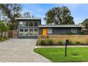 Mid-century modern home with gray exterior, orange door, and wood fence at 4708 W Oklahoma Ave, Tampa, FL 33616