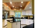 Modern kitchen with white cabinetry, granite countertops, and wood accent ceiling at 37210 Bermont Rd, Punta Gorda, FL 33982