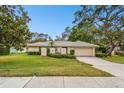 Tan one-story house with a two-car garage and lush green lawn at 970 Rolling Hills Dr, Palm Harbor, FL 34683