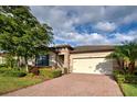 House exterior featuring a brick driveway and lush landscaping at 11976 Blazing Star Dr, Venice, FL 34293