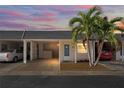 Evening view of a condo with carport, landscaping, and palm trees at 224 Sky Loch E Dr, Dunedin, FL 34698