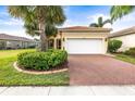 Inviting single-story home featuring a brick driveway, lush landscaping, and a two-car garage at 4817 Sandy Glen Way, Wimauma, FL 33598
