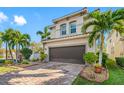 Two-story house with brown garage door, landscaping, and brick paver driveway at 4943 Grand Oak Cir, Madeira Beach, FL 33708