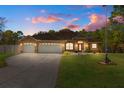 Attractive one-story home with three-car garage and manicured lawn at dusk at 5171 Bone Ln, Brooksville, FL 34604