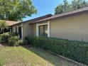 Tan home with lush greenery and manicured lawn on a bright, sunny day at 1669 Fry Ct, Dunedin, FL 34698