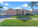 Inviting single-story home featuring a well-manicured lawn, arched entryway, and a three-car garage at 1406 Deerbourne Dr, Wesley Chapel, FL 33543