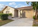 Tan house with brown roof, landscaping, and a two-car garage at 2020 San Sebastian S Way, Clearwater, FL 33763