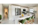 Modern kitchen featuring sleek white cabinetry, stainless steel appliances, waterfall island, and stylish backsplash at 12506 Forest Hills Dr, Tampa, FL 33612