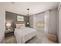 Well-lit bedroom with a white comforter, a bedside table, and wall decor at 23242 Alaska Ave, Port Charlotte, FL 33980