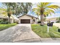 Inviting single-story home featuring a brick-paved driveway, lush lawn, and mature palm trees for a tropical curb appeal at 6208 Spoonbill Dr, New Port Richey, FL 34652