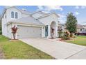 Charming two-story home with a well-manicured lawn, arched entrance, and attached two-car garage at 4104 Warwick Hills Dr, Wesley Chapel, FL 33543