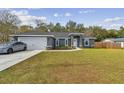 Gray house with white garage door, and green lawn at 6103 Fairway Dr, Ridge Manor, FL 33523